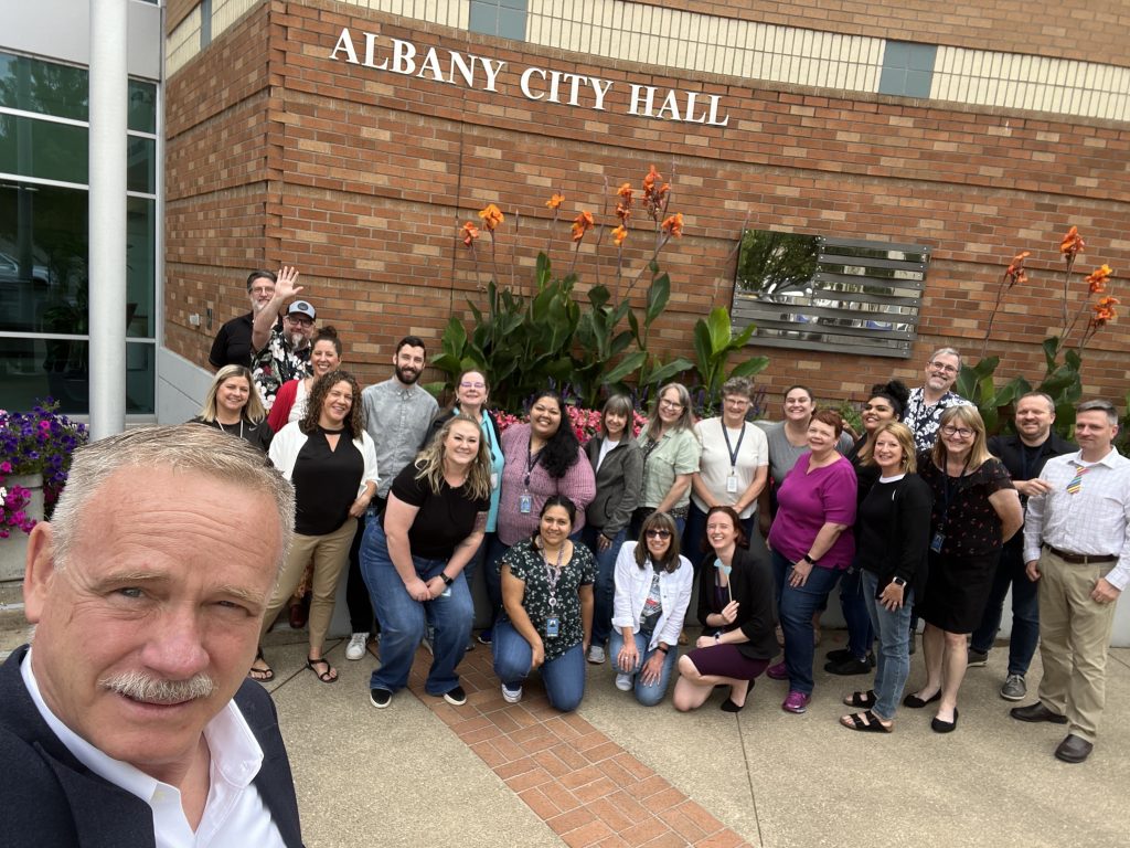 Group selfie of various employees including the City Manager outside City Hall for City Hall Selfie Day in 2024.
